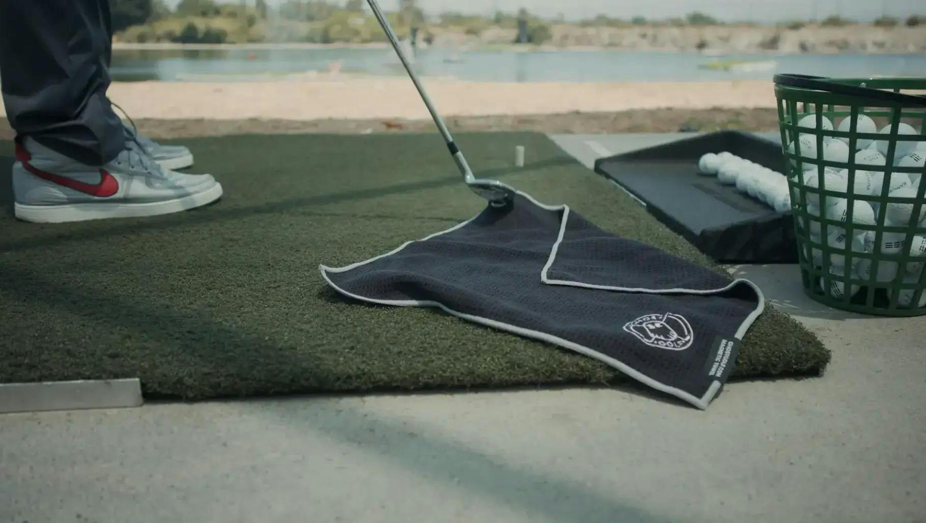 Een handdoek van Ghost Golf op de vloer van een driving range 